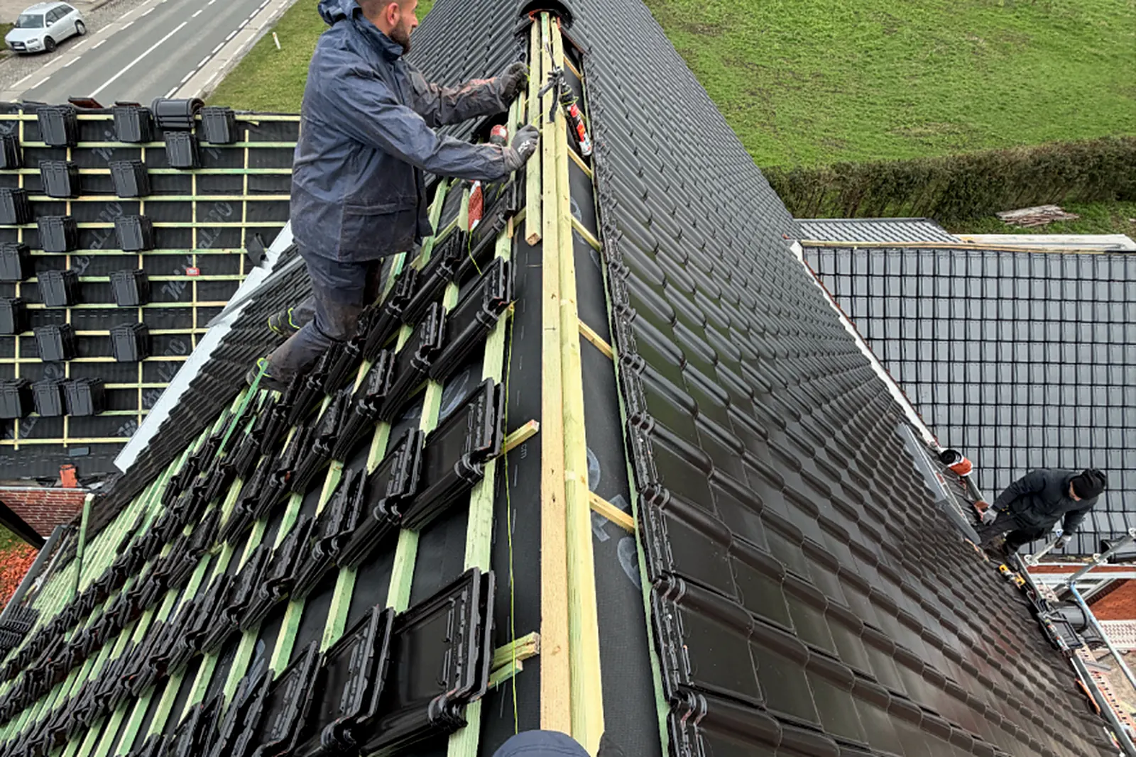 Dakwerkers leggen dakpannen en werken de nok af op een hellend dak