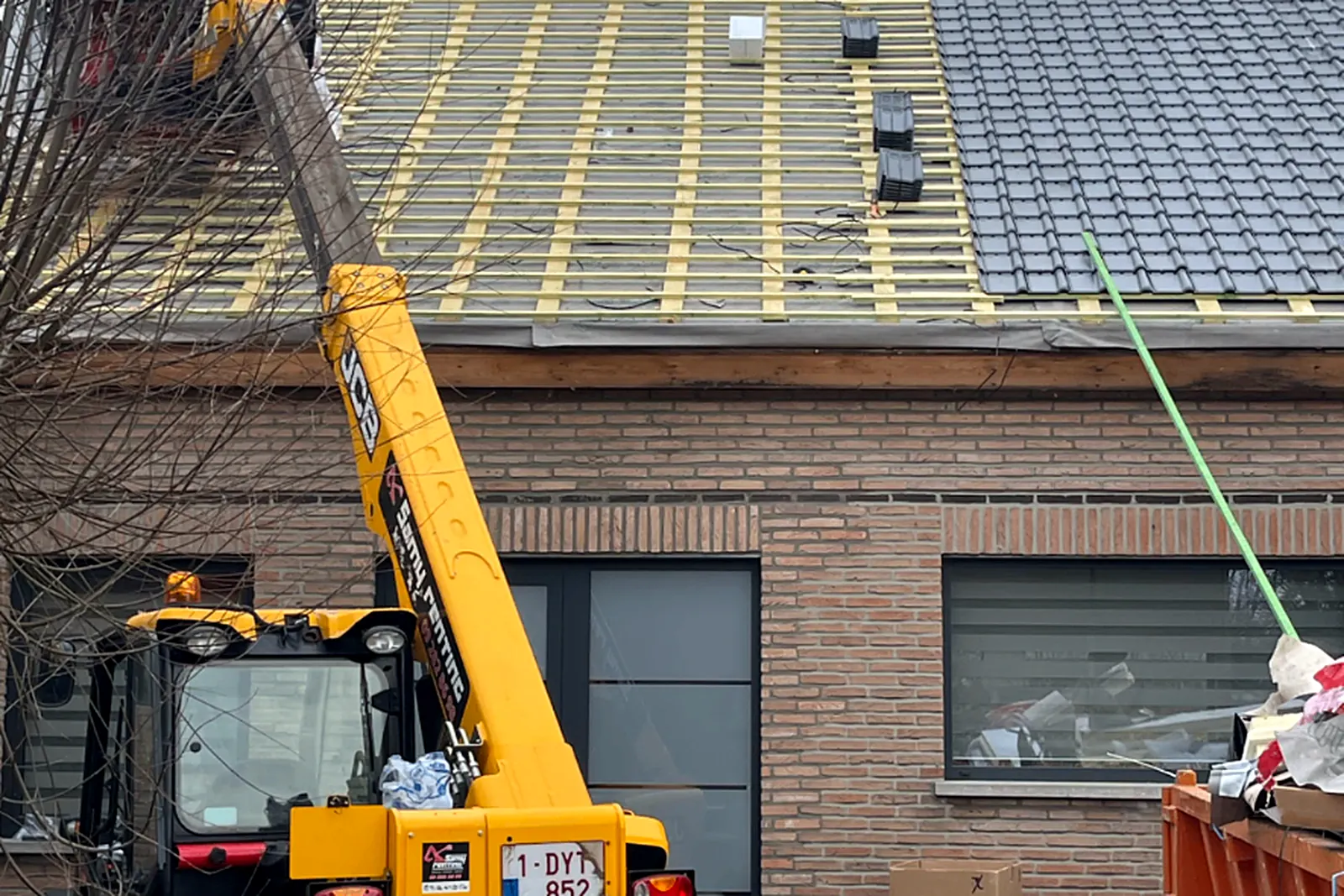 Hellend dak met onderdak en panlatten, materiaal aangevoerd met een verreiker