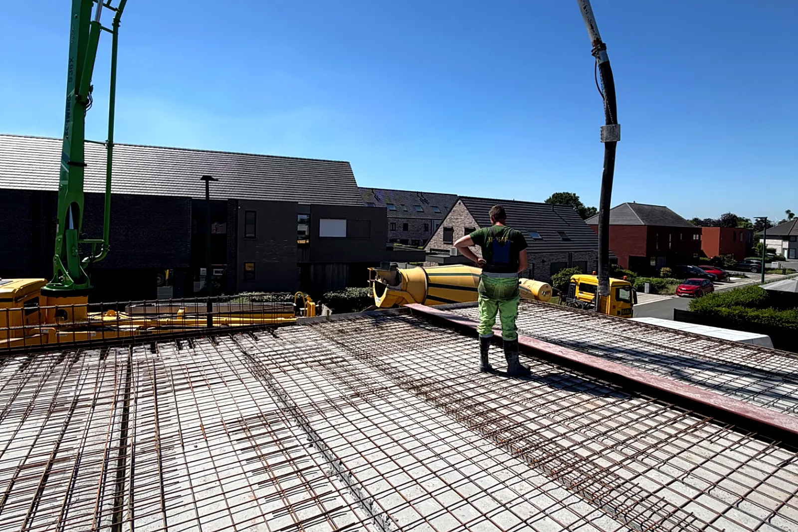 Betonpomp en mixers bij het storten van de gewapende vloerplaat van een nieuwbouwwoning door Demir Group